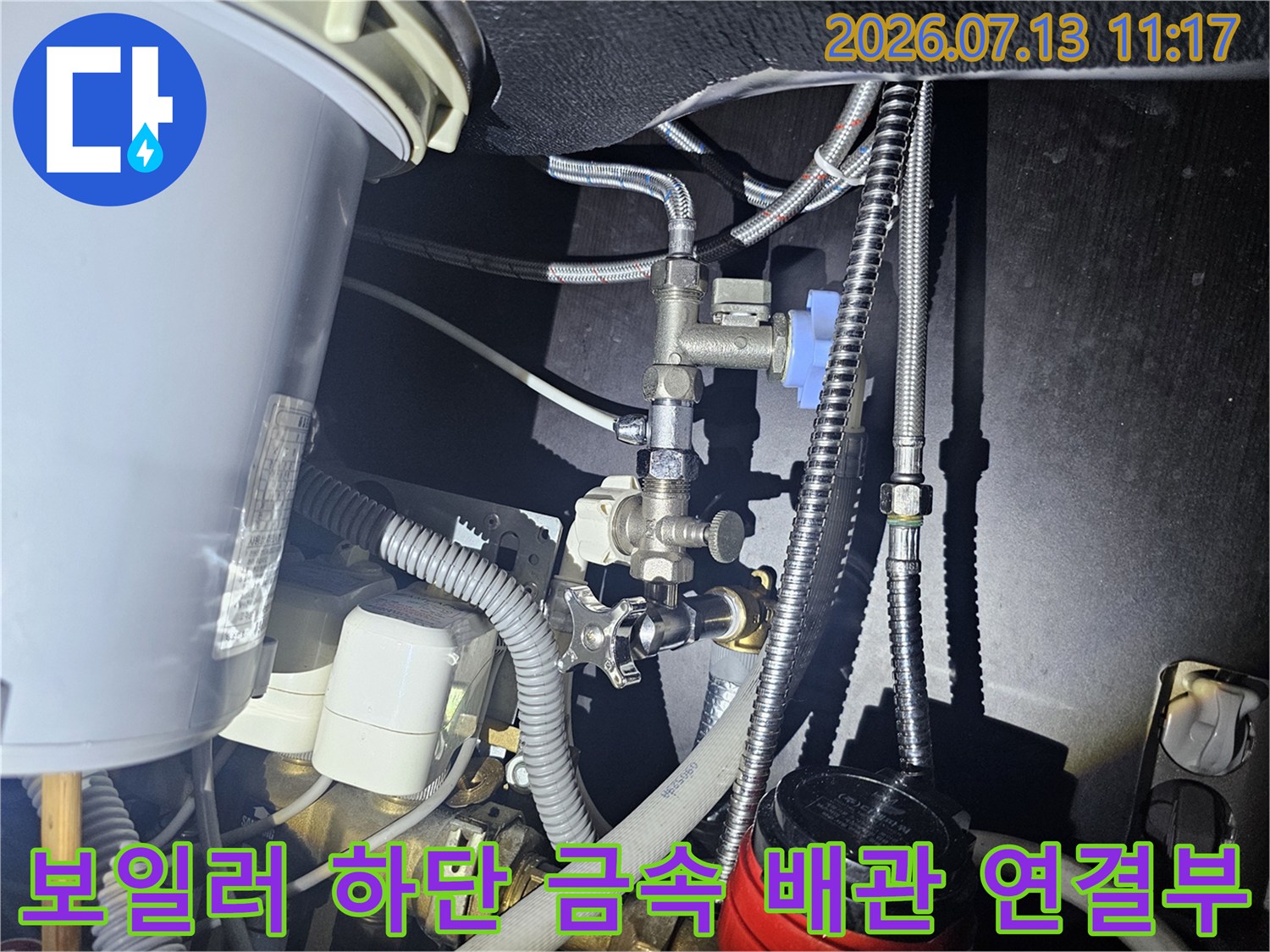 보일러 하단에 설치된 금속 재질의 복잡한 배관 라인과 밸브 모습