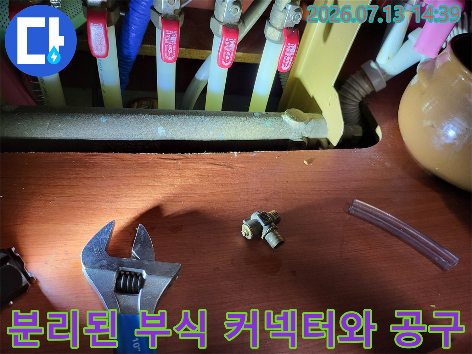 누수의 주범이었던 작은 금속 연결재-몽키스패너와 투명 호스가 함께 놓인 사진