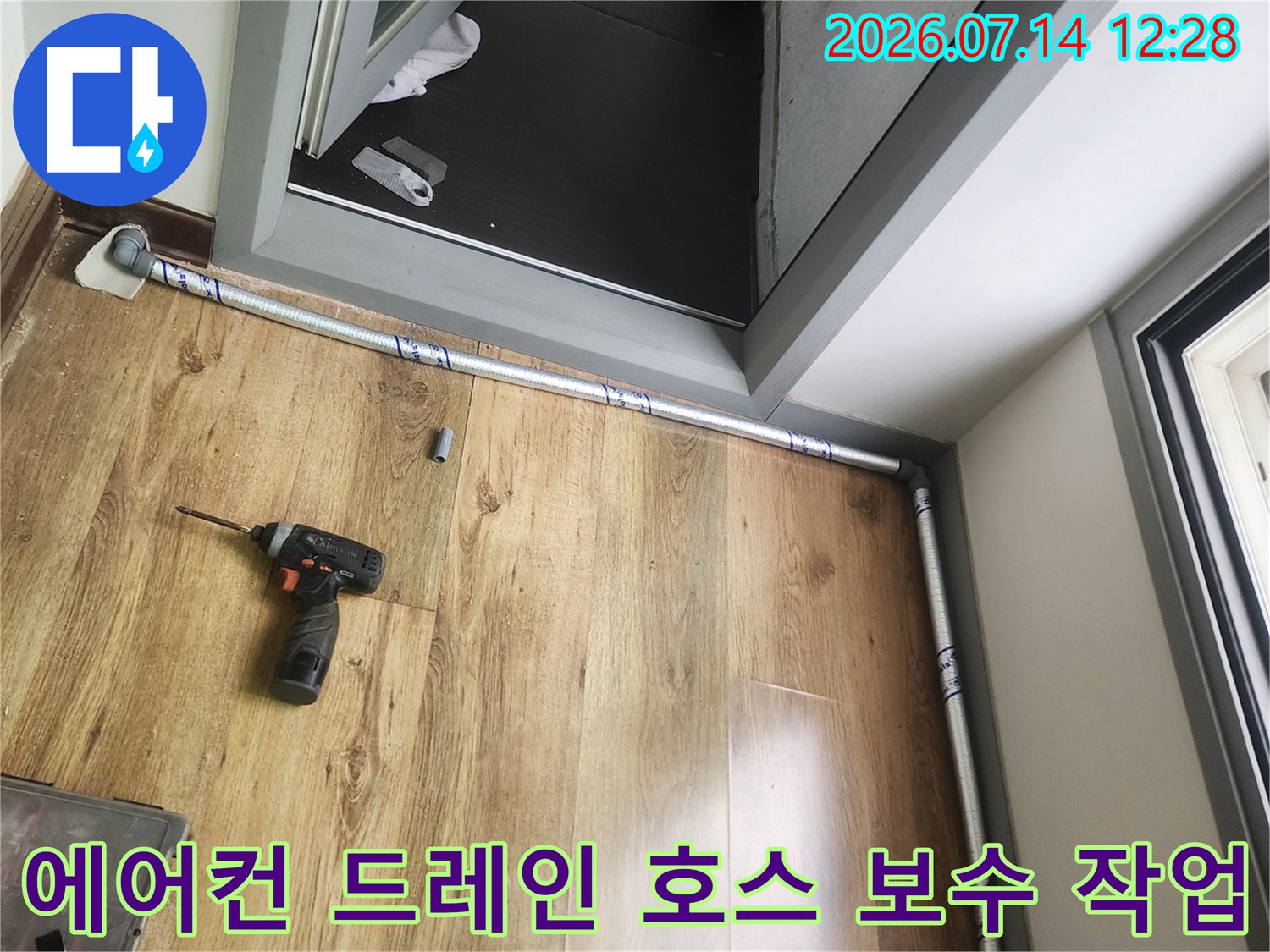 베란다 바닥에 놓인 장비와 에어컨 드레인 배출 호스가 설치된 모습