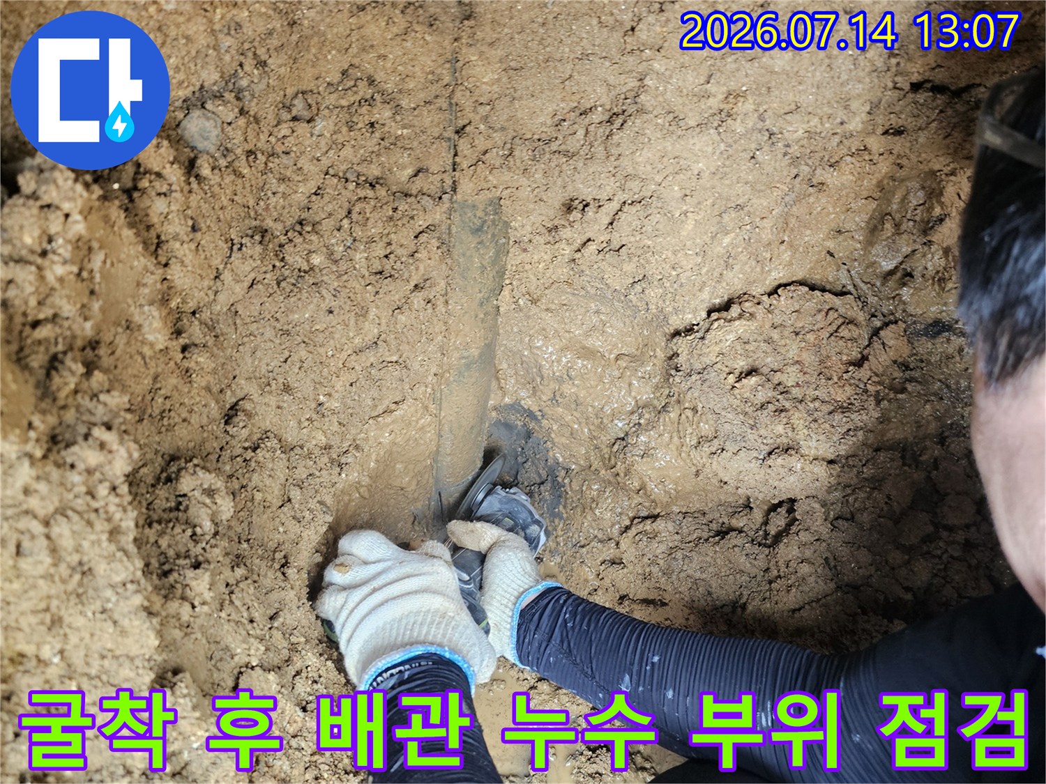 파헤쳐진 흙 속에서 물이 새는 배관 연결부위를 조심스럽게 확인하는 작업 현장