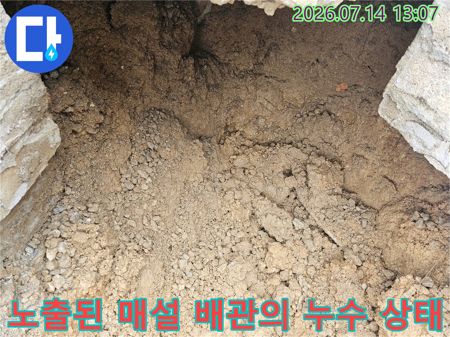 흙과 돌이 섞인 지표면 아래 노출된 수도 배관 부위