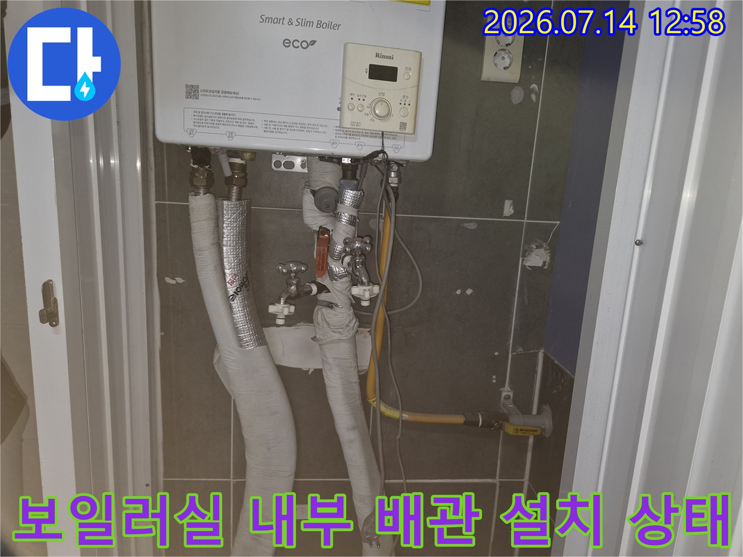벽면에 고정된 보일러 아래로 복잡하게 얽힌 하얀색 단열재 배관과 가스 공급 라인