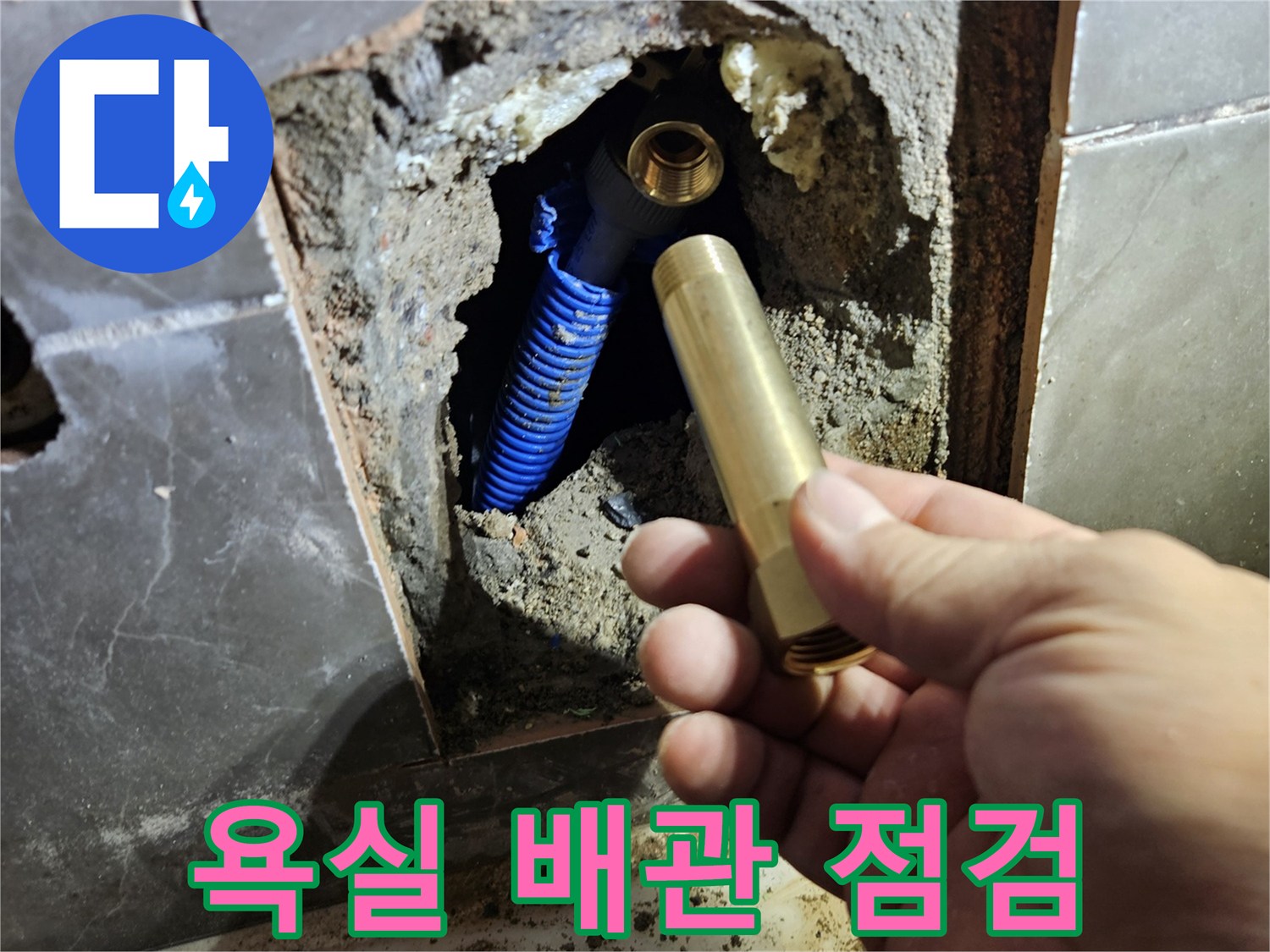 욕실 타일을 제거하고 내부 파란색 배관과 수전 부속을 확인하는 모습