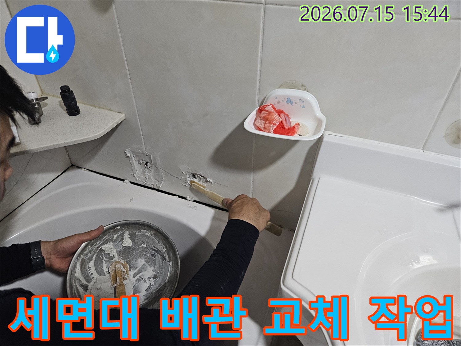 작업자가 세면대 밑 노출된 파이프 부위를 수선하는 모습