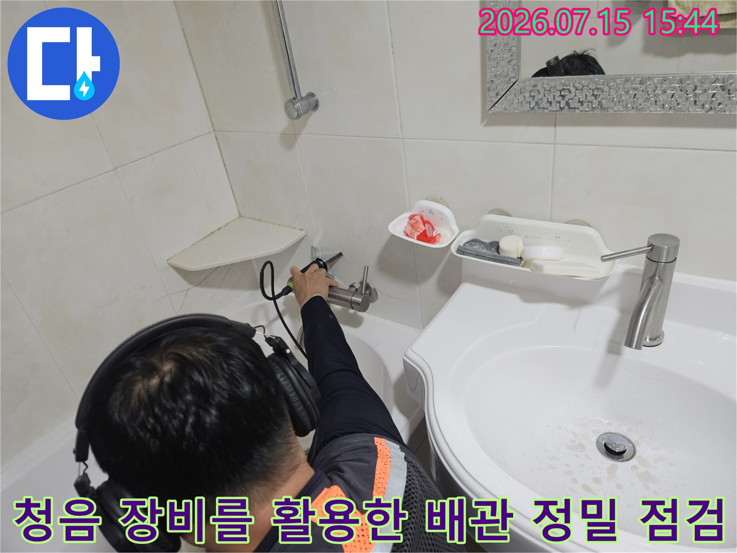 전문가용 청음기를 사용하여 세면대 아래 노후된 배관의 누수음을 감지하는 장면