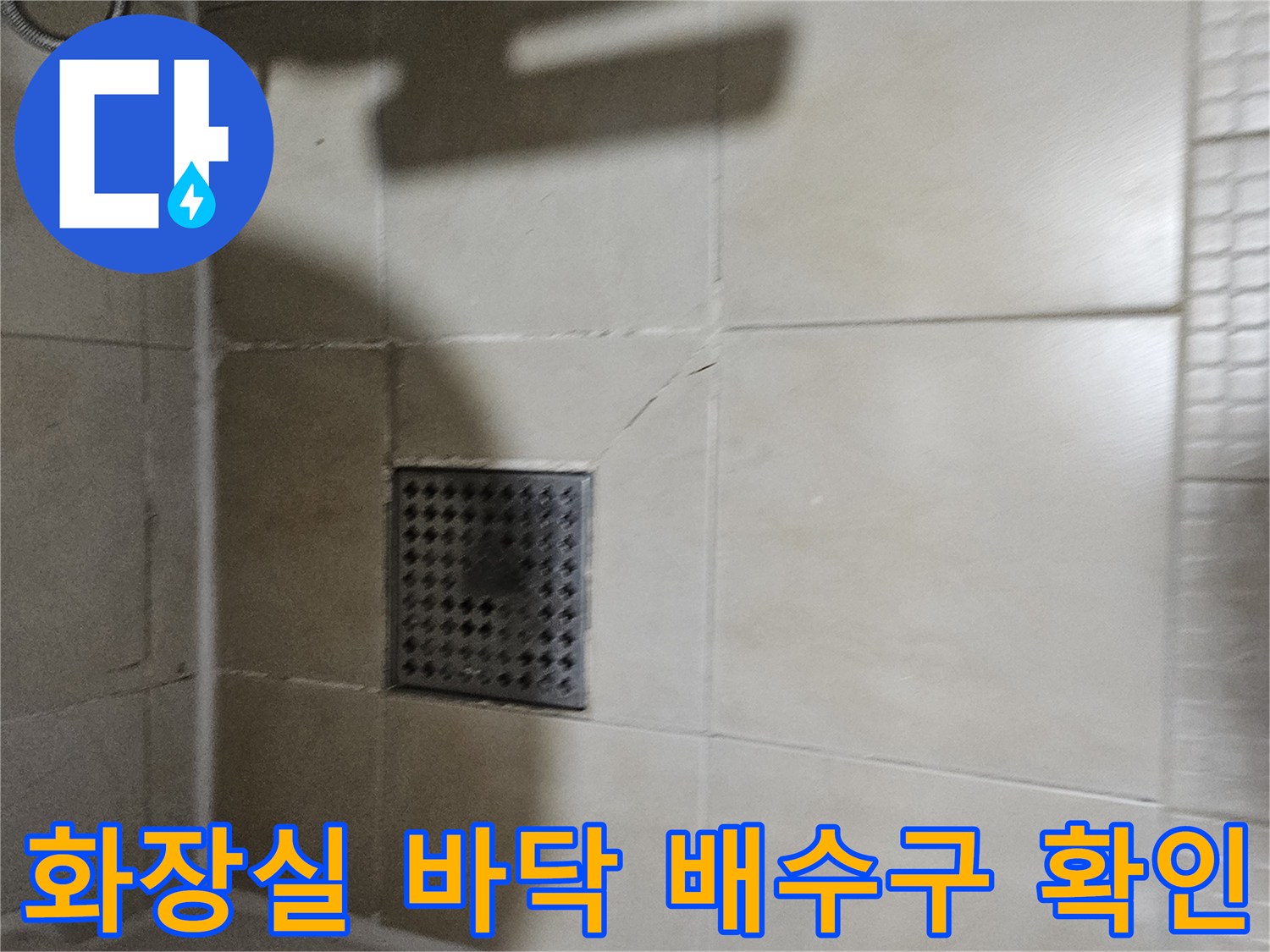타일 사이의 균열과 배수구 격자 덮개 상태를 보여주는 사진입니다.