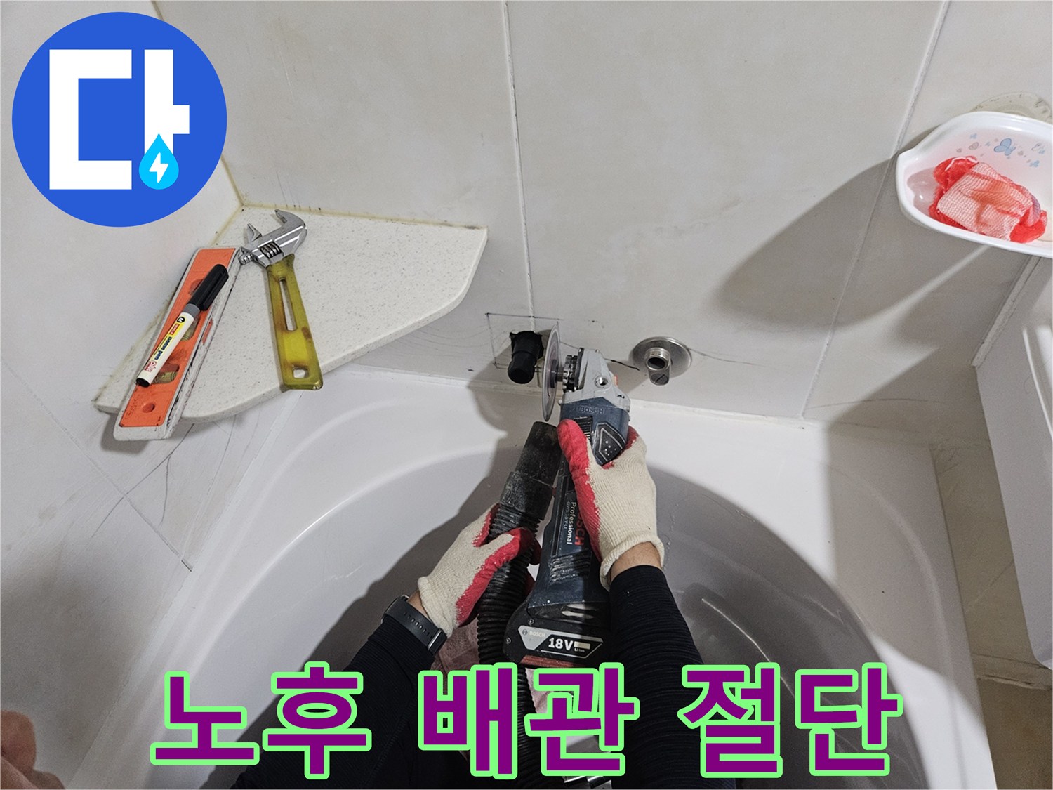 화장실 벽면 타일 부근-전동 장비로 배관을 자르는 작업자 모습