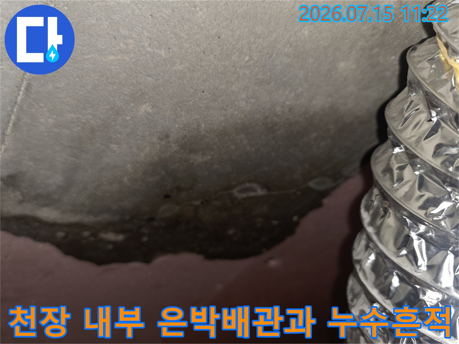 은박 보온재로 마감된 배관 옆으로 넓게 퍼져 있는 천장의 어두운 색 누수 얼룩