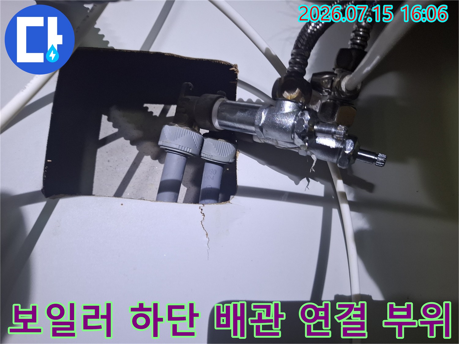 보일러 하단부의 금속 밸브와 플라스틱 배관이 연결된 모습-누수 점검 과정