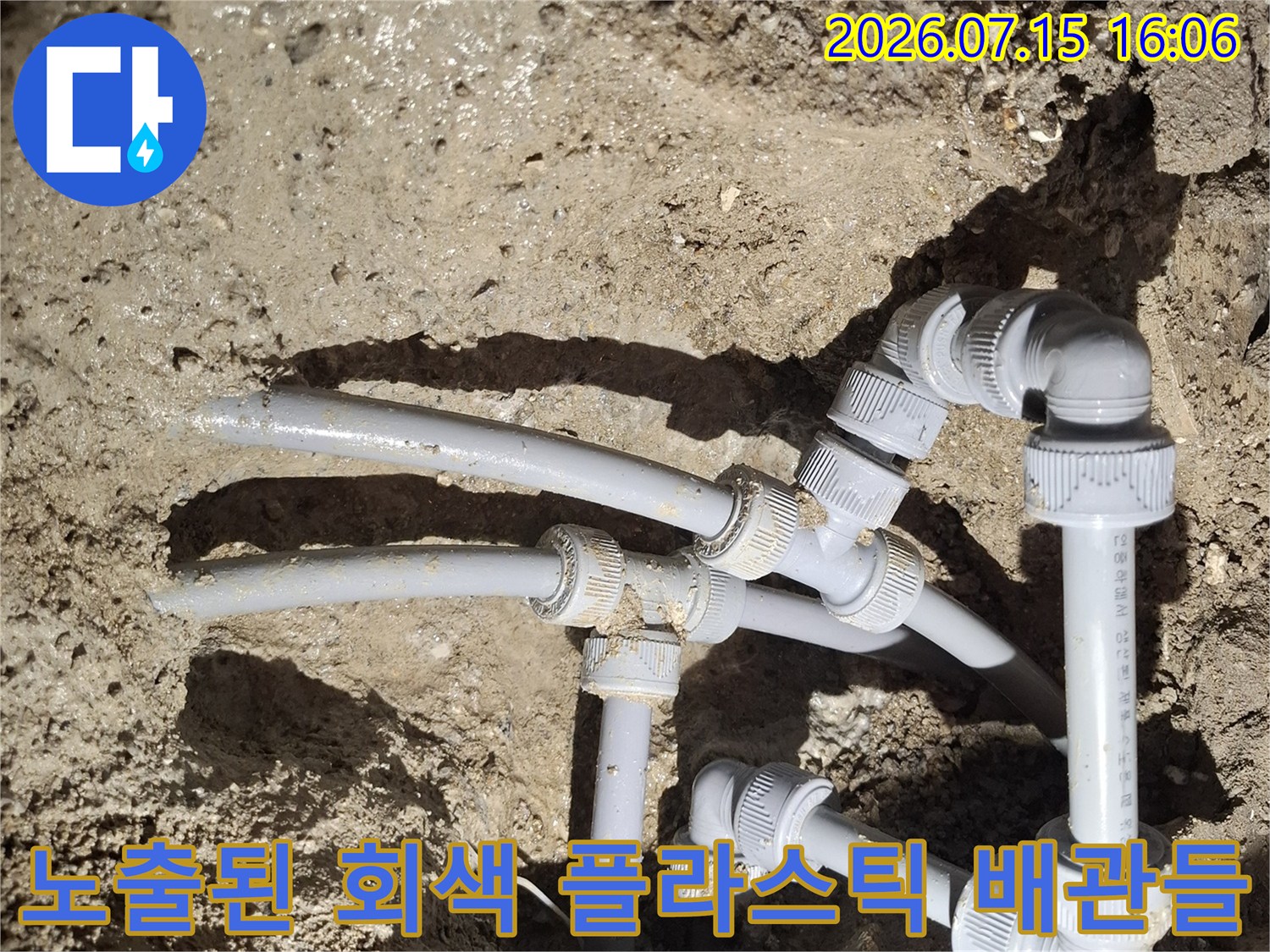 흙과 모래 사이로 드러난 여러 개의 회색 수도 배관 연결 지점들