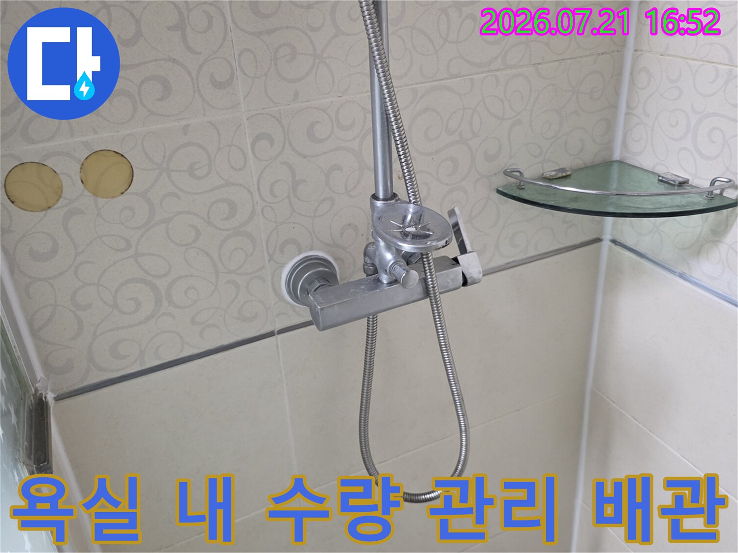 화장실 벽면에 고정된 샤워기 관련 부속과 배관의 모습