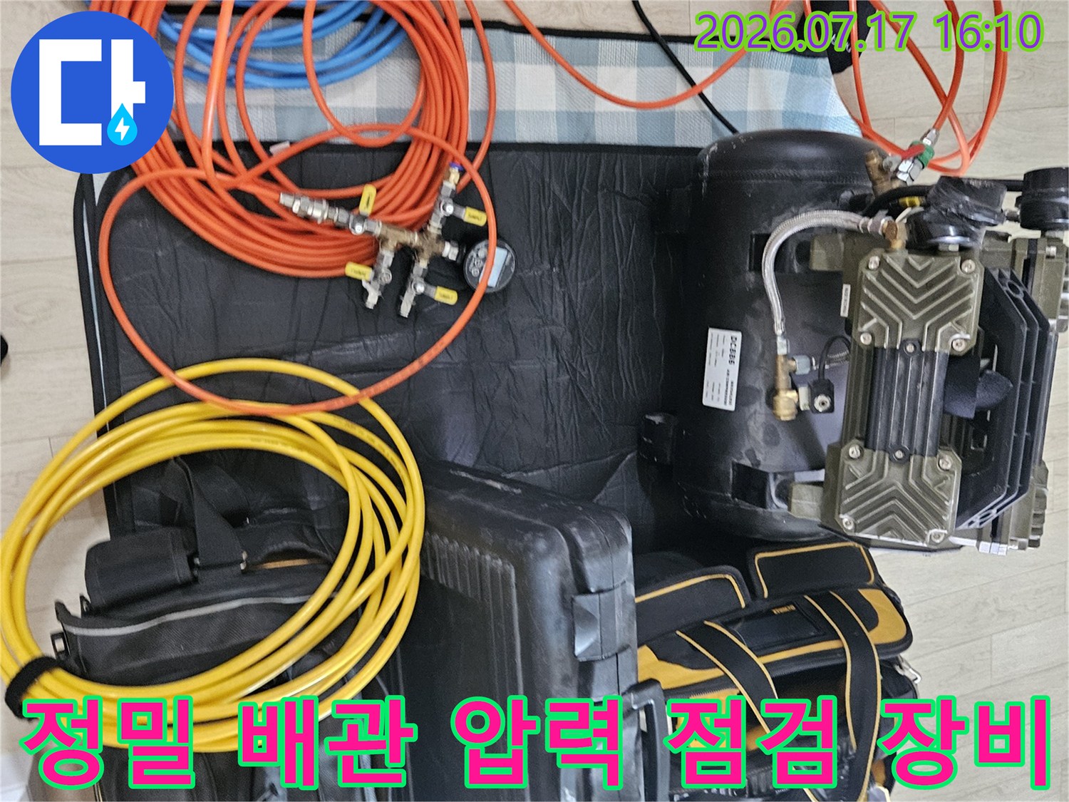 공압 테스트를 위해 연결된 오렌지색과 노란색 호스 및 게이지와 펌프 세트