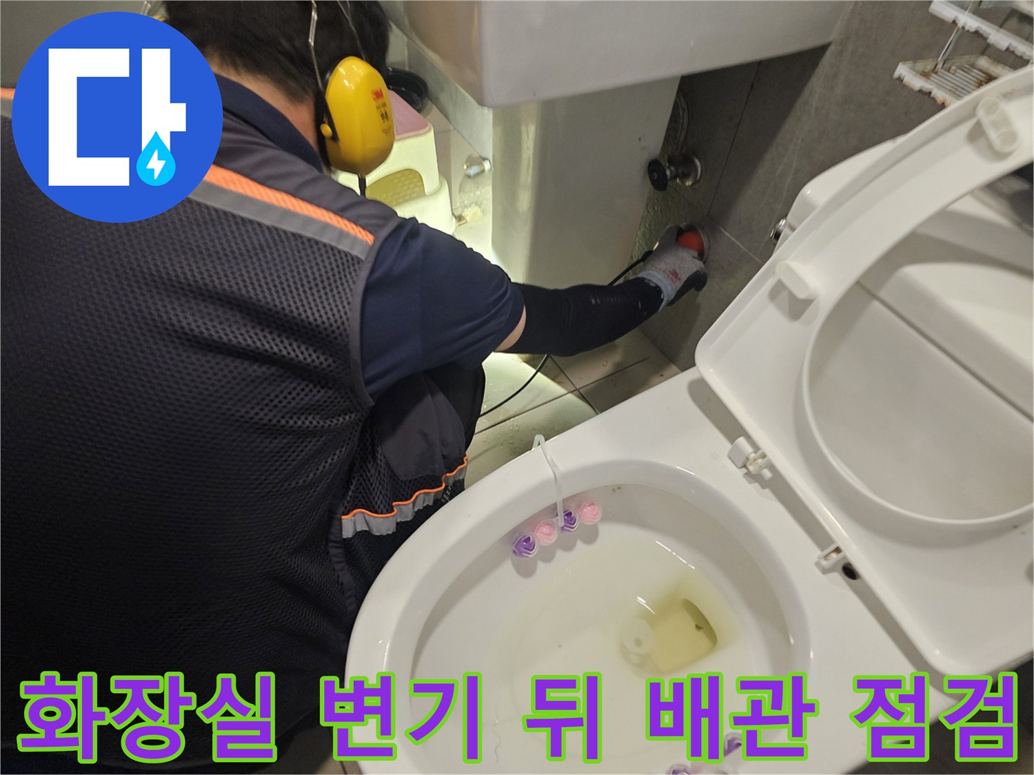 변기 뒤쪽 벽면의 배관 연결 부위를 엔지니어가 꼼꼼하게 확인하고 있습니다.