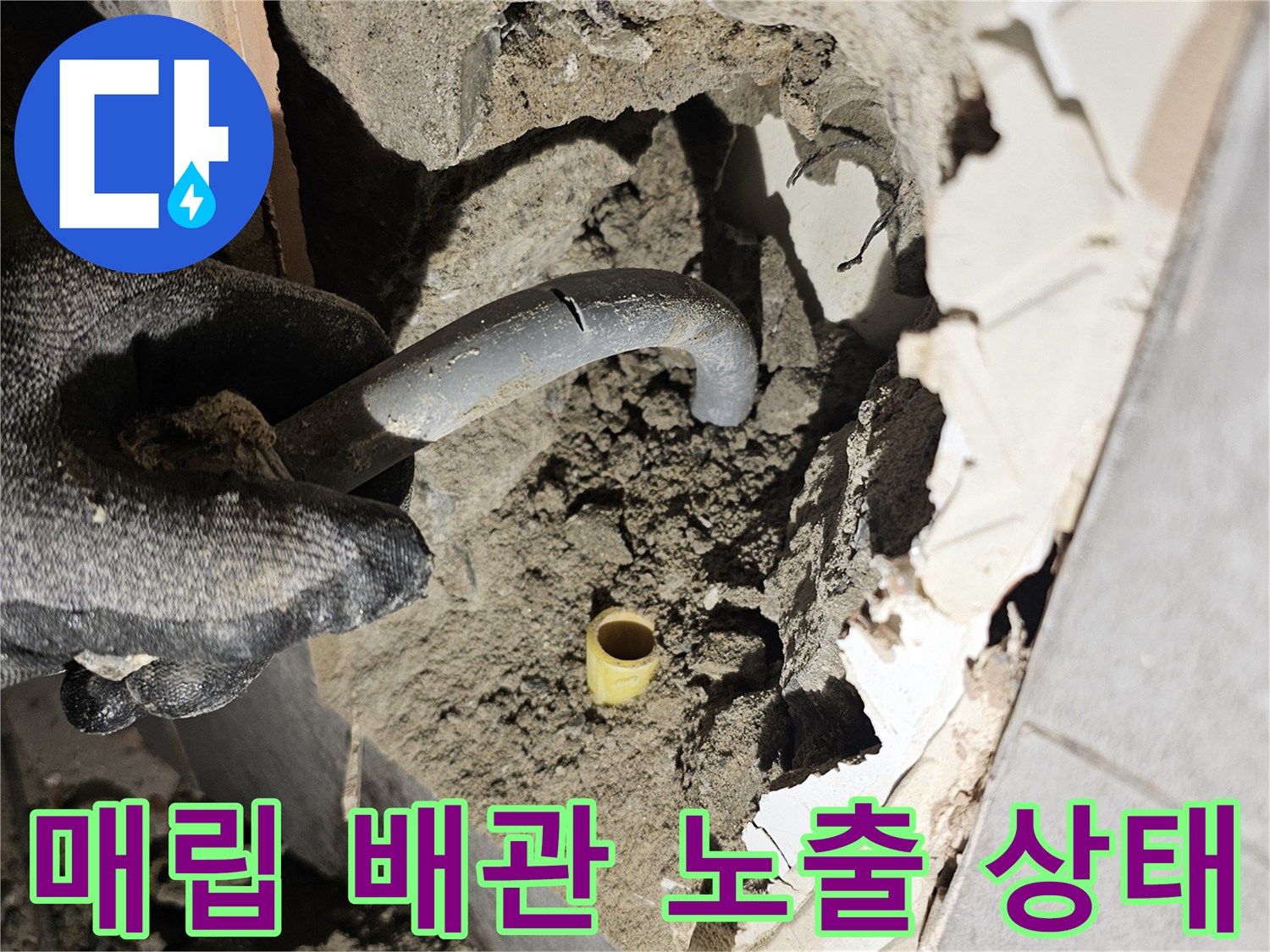 타일 아래 흙과 콘크리트 사이에 드러난 노란색 배관 부속