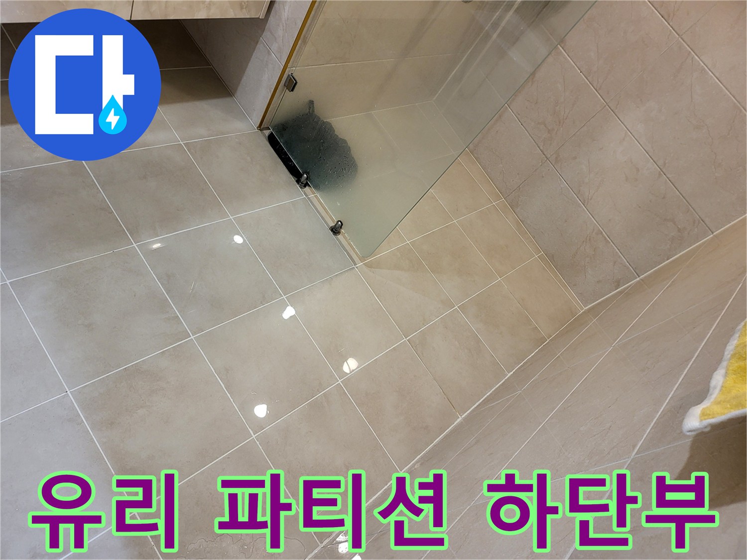 샤워실 유리 파티션과 베이지색 바닥 타일의 경계 부분