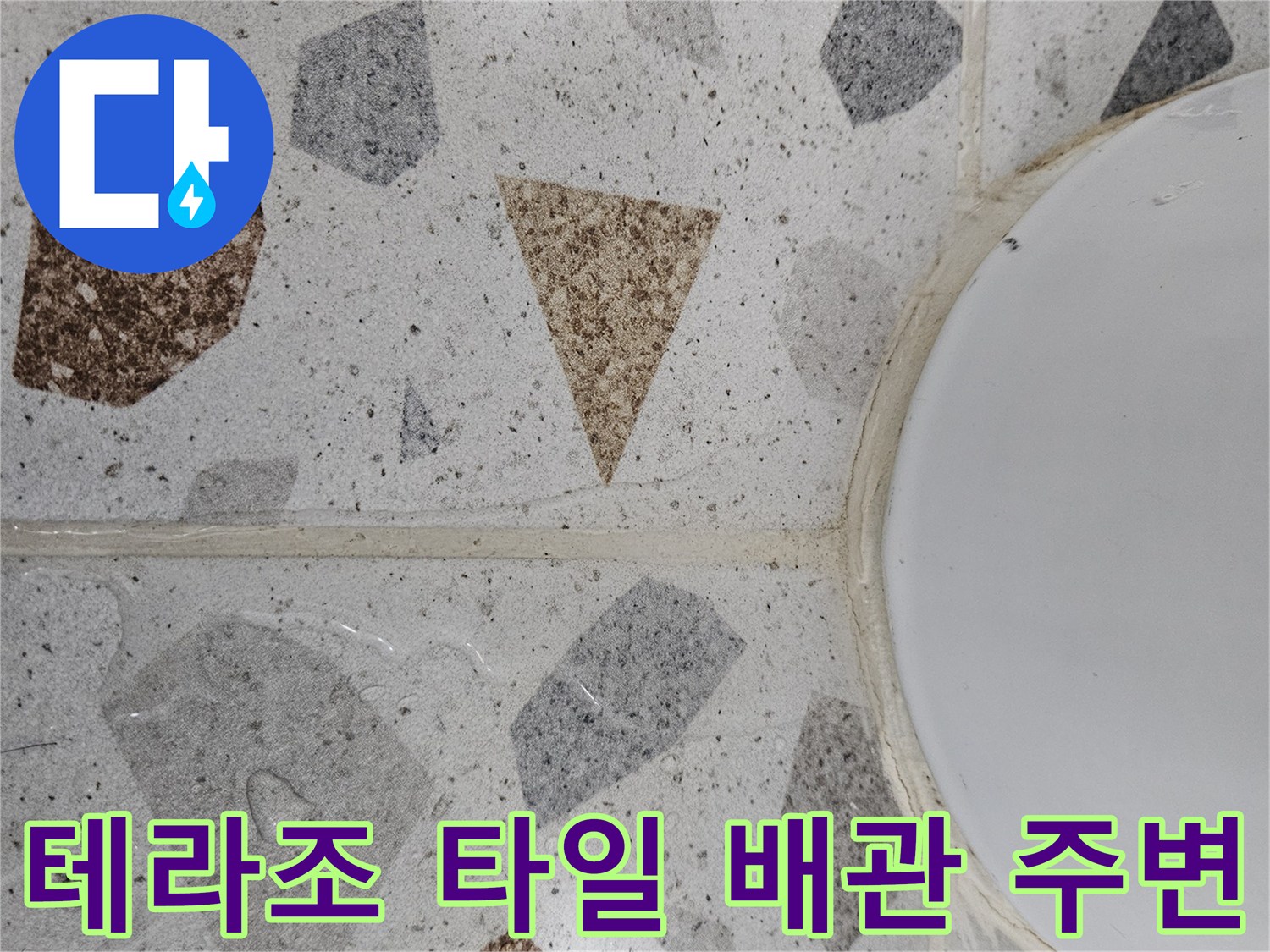 테라조 무늬 타일과 흰색 배관 연결 부위 근접 사진