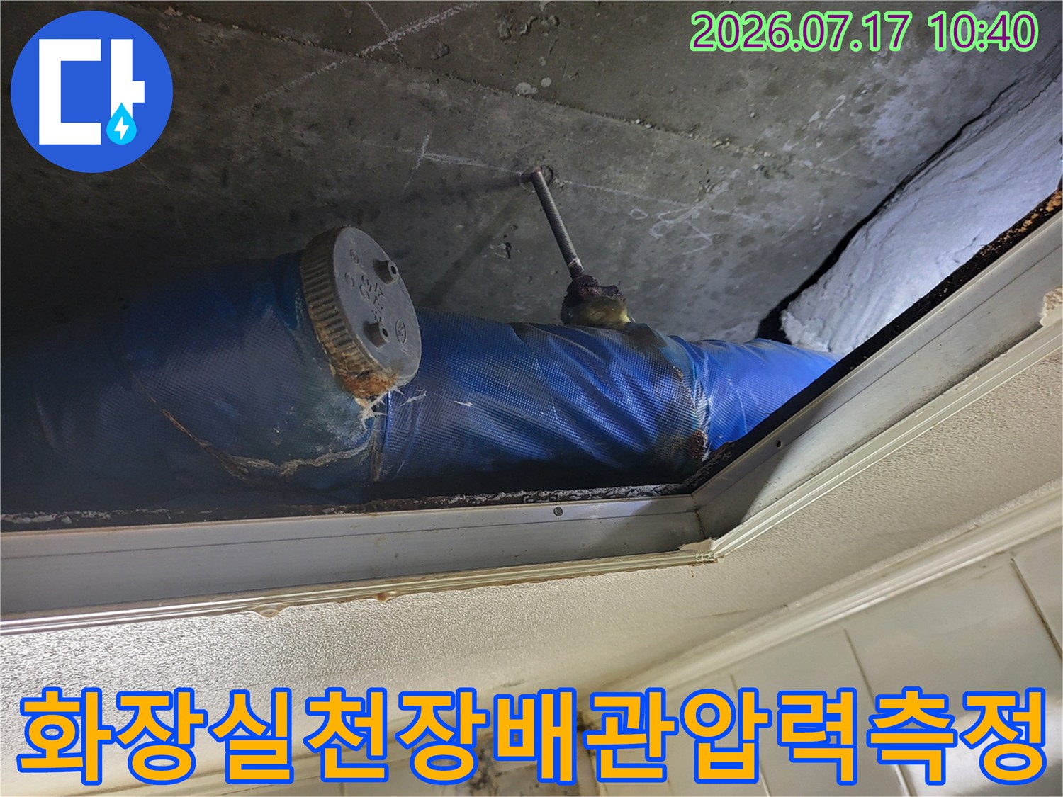 파란색 보온재로 감싸진 배관에 압력 게이지를 연결하여 누수 여부를 정밀하게 점검하는 모습