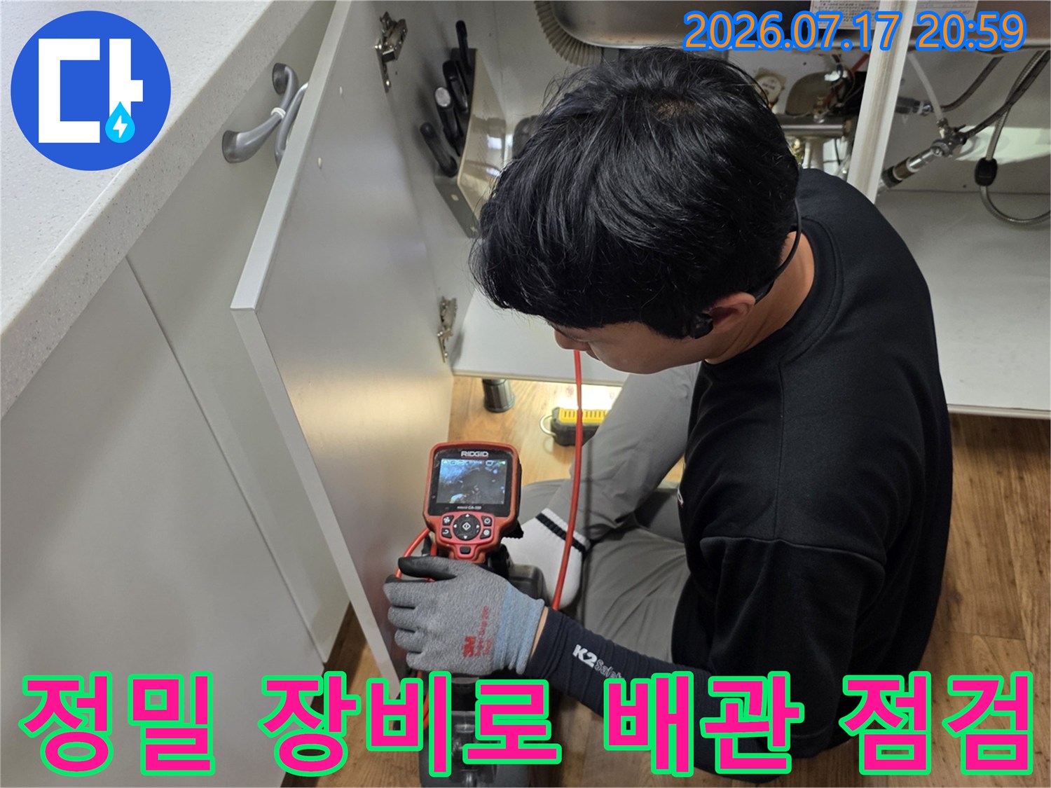 엔지니어가 싱크대 하부에서 전용 탐지기를 사용하여 배수 배관의 상태를 정밀하게 체크하는 모습