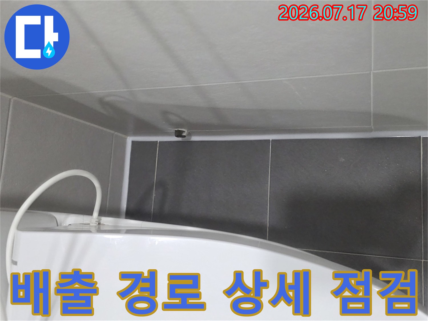 욕실 내부의 배출 파이프라인과 타일 마감 부위를 근접하여 촬영한 사진