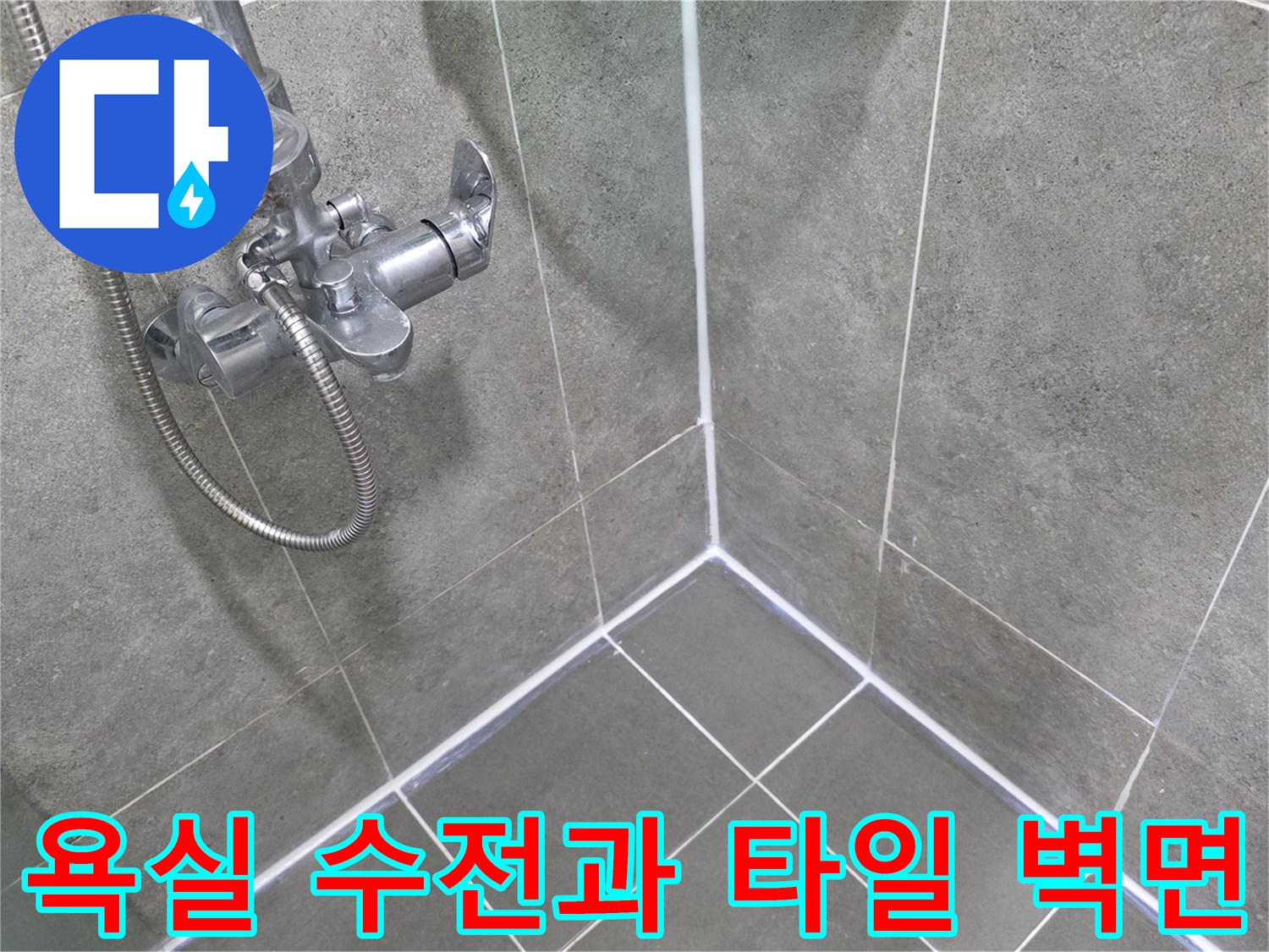 회색 타일로 마감된 욕실 벽면의 수전 및 샤워기 호스 모습