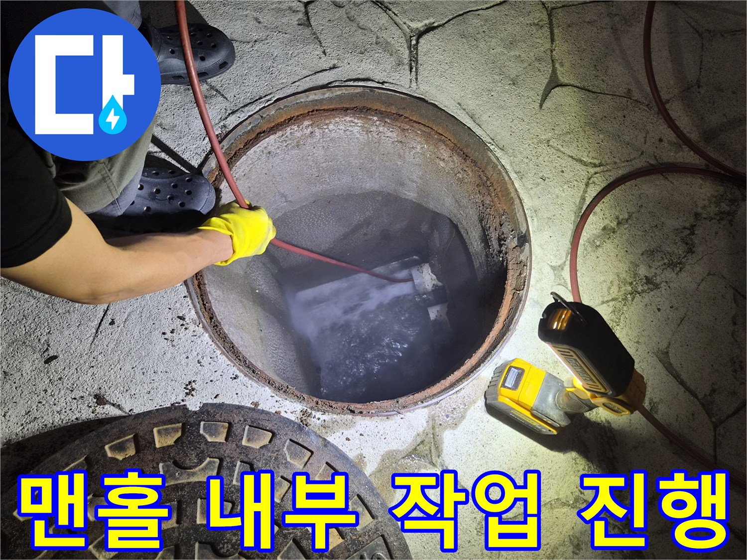작업자가-맨홀-안쪽으로-장비를-투입하는-모습