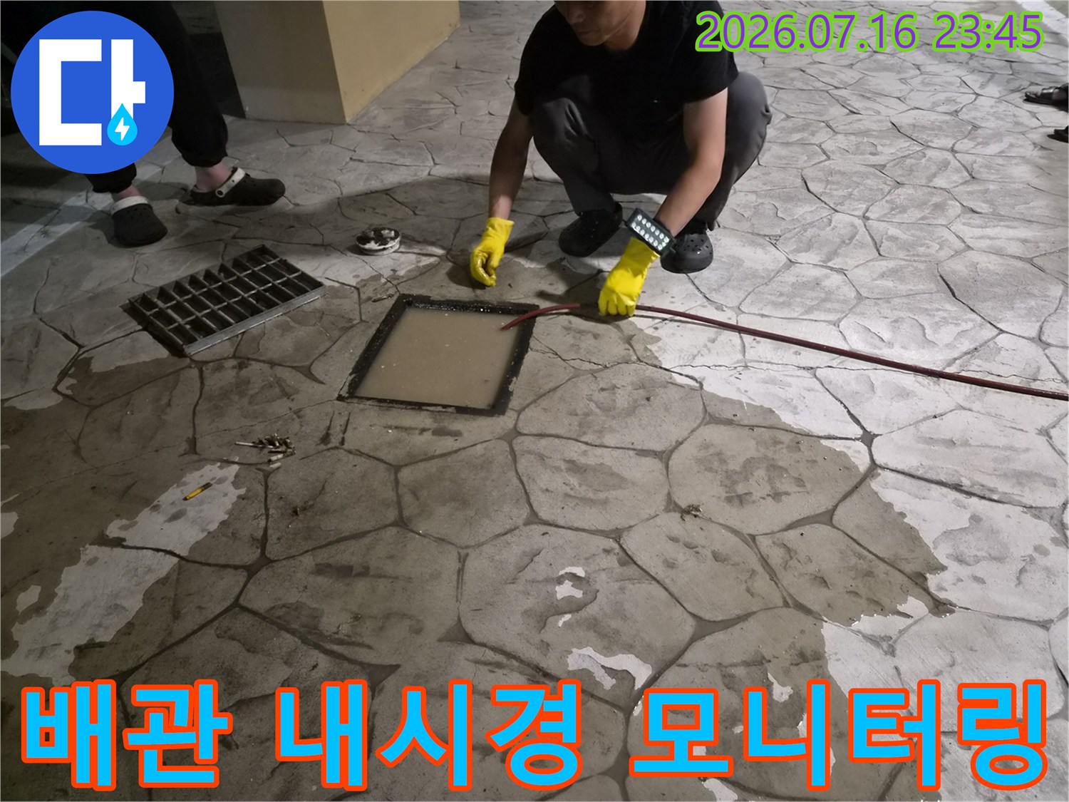 전문가가 노란 장갑을 끼고 내시경 장비를 조절하며 배관 안쪽을 살피는 모습