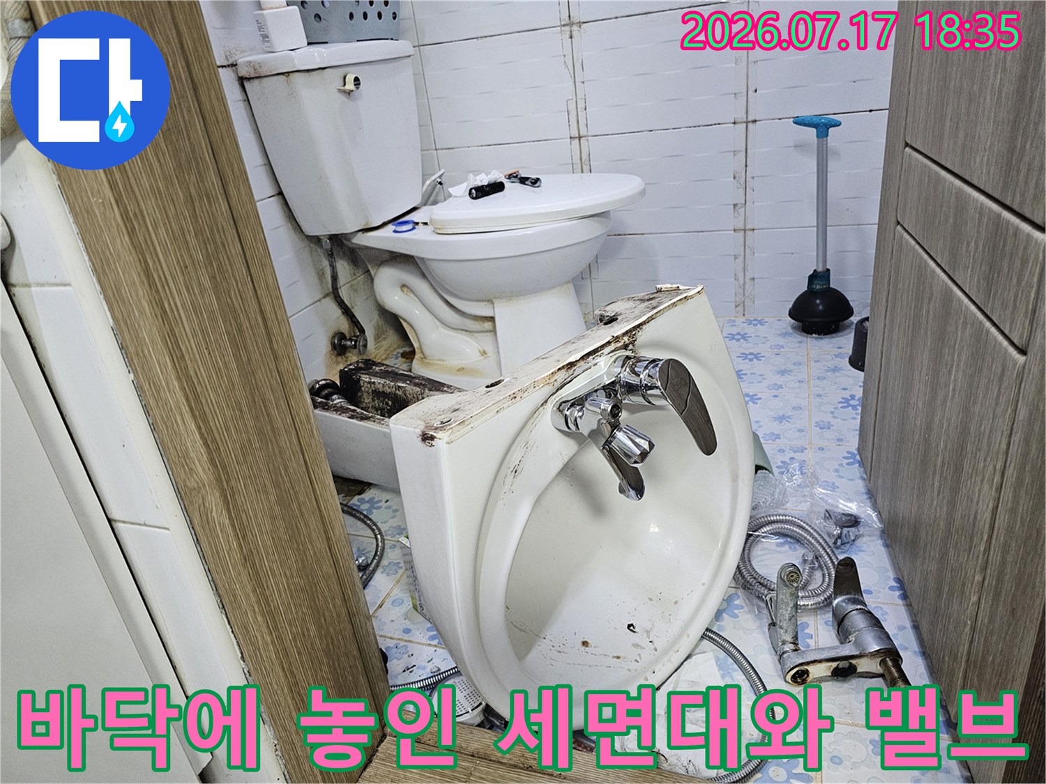 흰색 도기제 세면대가 타일 바닥에 있으며-뒤쪽으로 변기가 보임