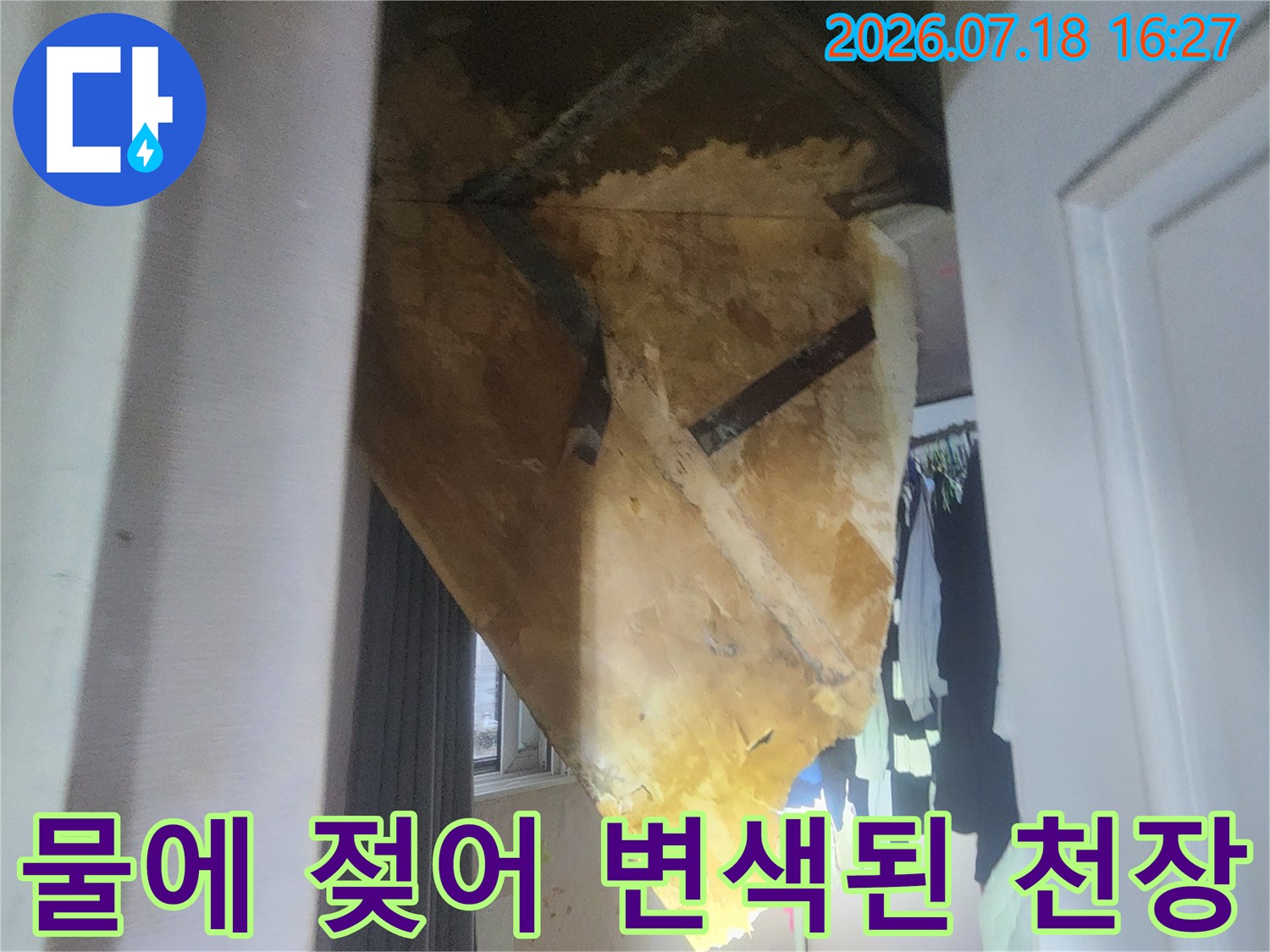 천장의 벽지와 마감재가 누수로 인해 갈색으로 오염된 모습