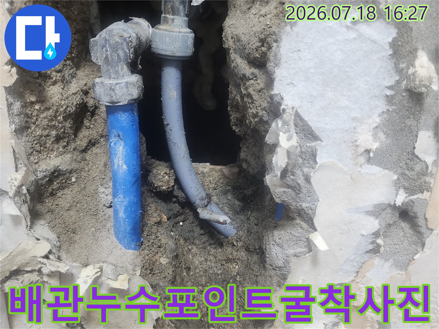 흙과 시멘트 속에 파묻혀 있다가 굴착으로 드러난 파란색 수도 관-누수 부위 확인