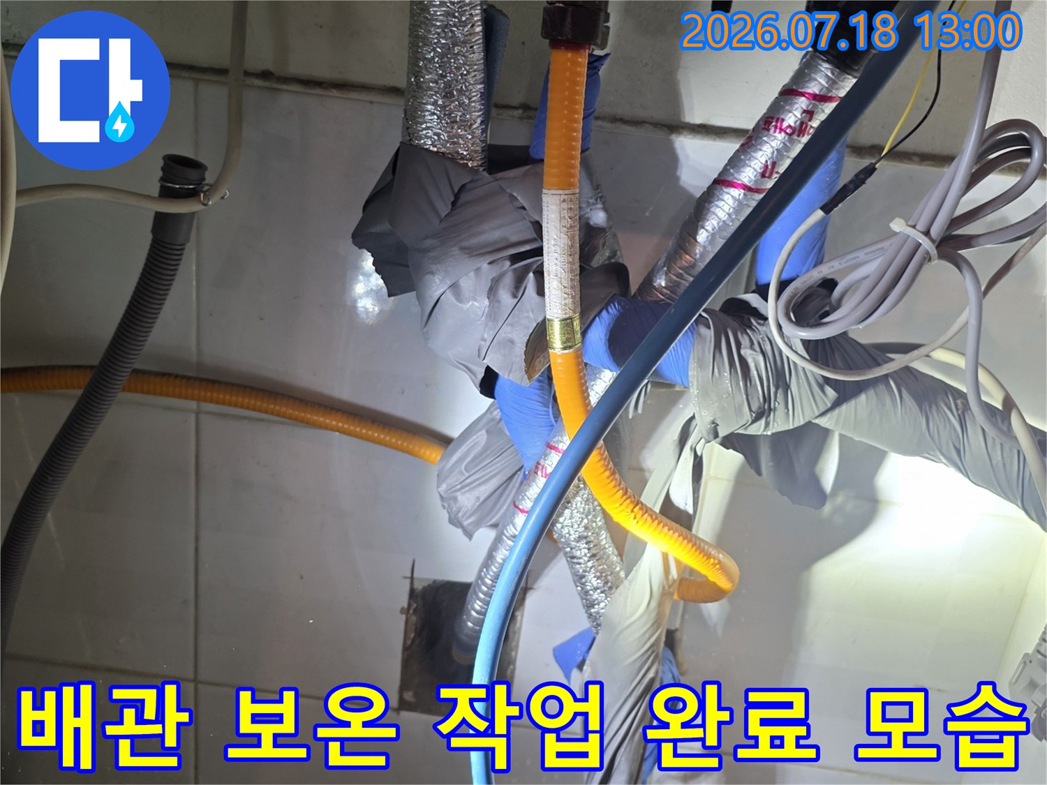 노란색-은색의 보온재로 감싸진 배관들이 파란색 호스와 함께 설치된 장면