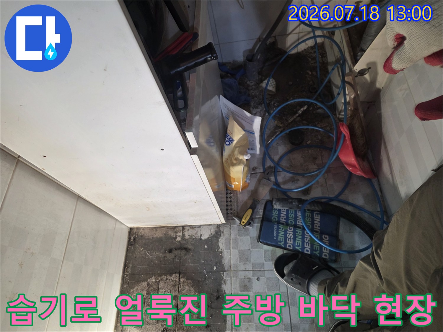 물기가 가득해 변색된 타일 위에 놓인 푸른색 수도 배관-누수 점검 과정