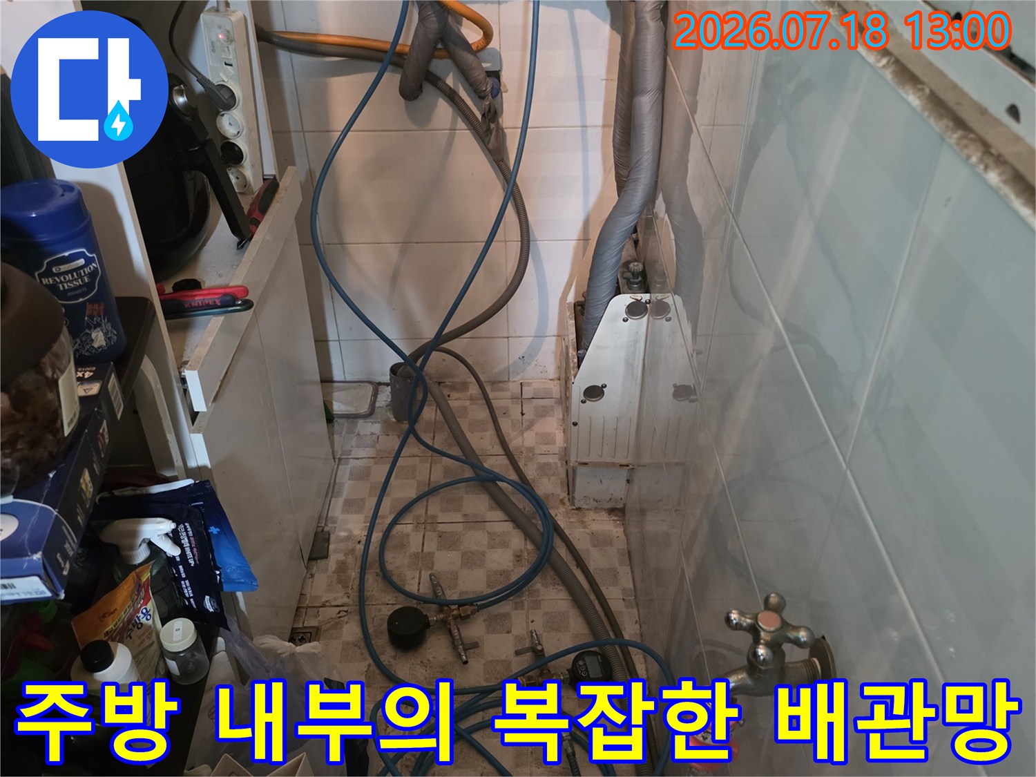 벽면에 고정된 금속제 수도 밸브와 그 아래로 연결된 파란색 유연 호스들