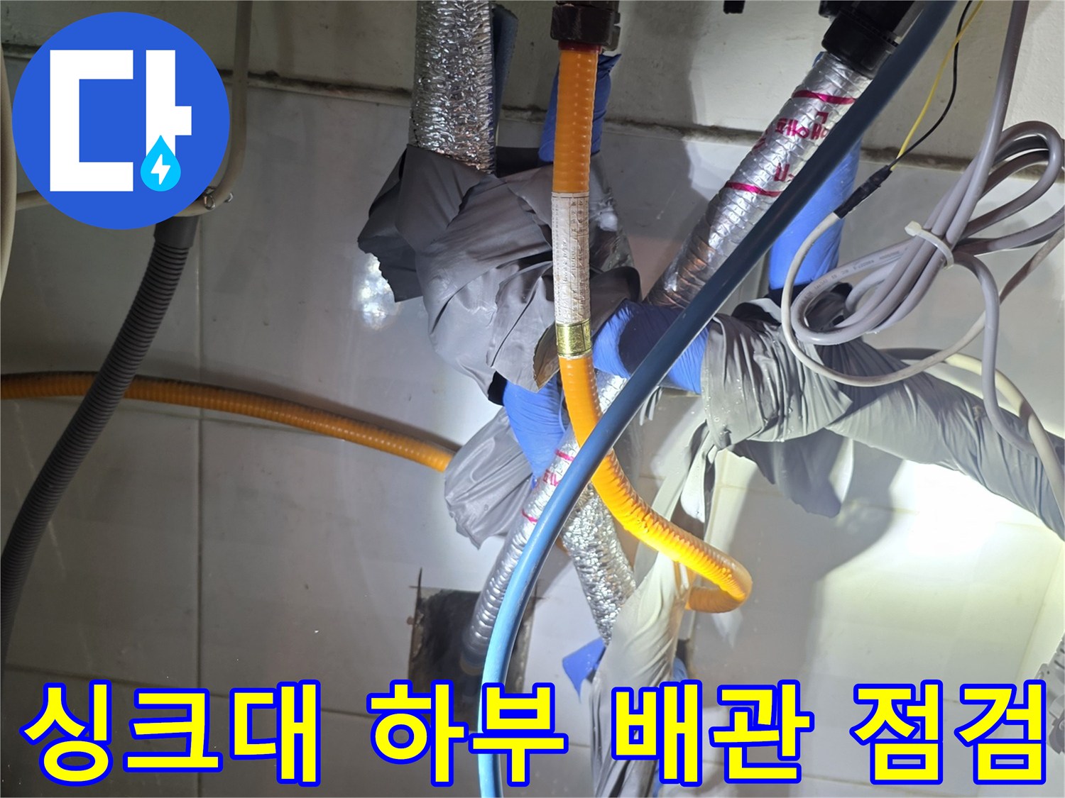 은색 보온재와 파란 호스가 얽힌 주방 배관 모습
