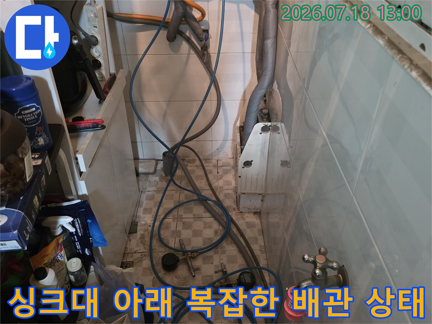 주방 싱크대 하단에 설치된 파란색 호스와 수도 밸브-배관 연결 부위 모습