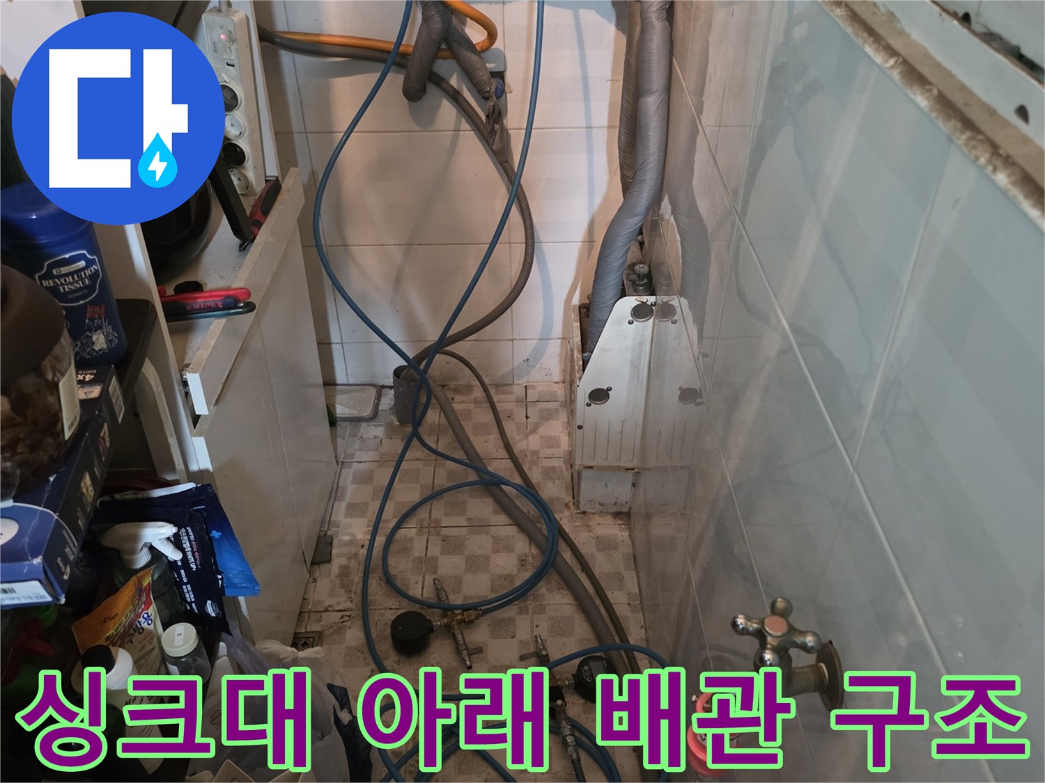 주방 하부장 내부의 다양한 수전 밸브와 호스 연결 모습