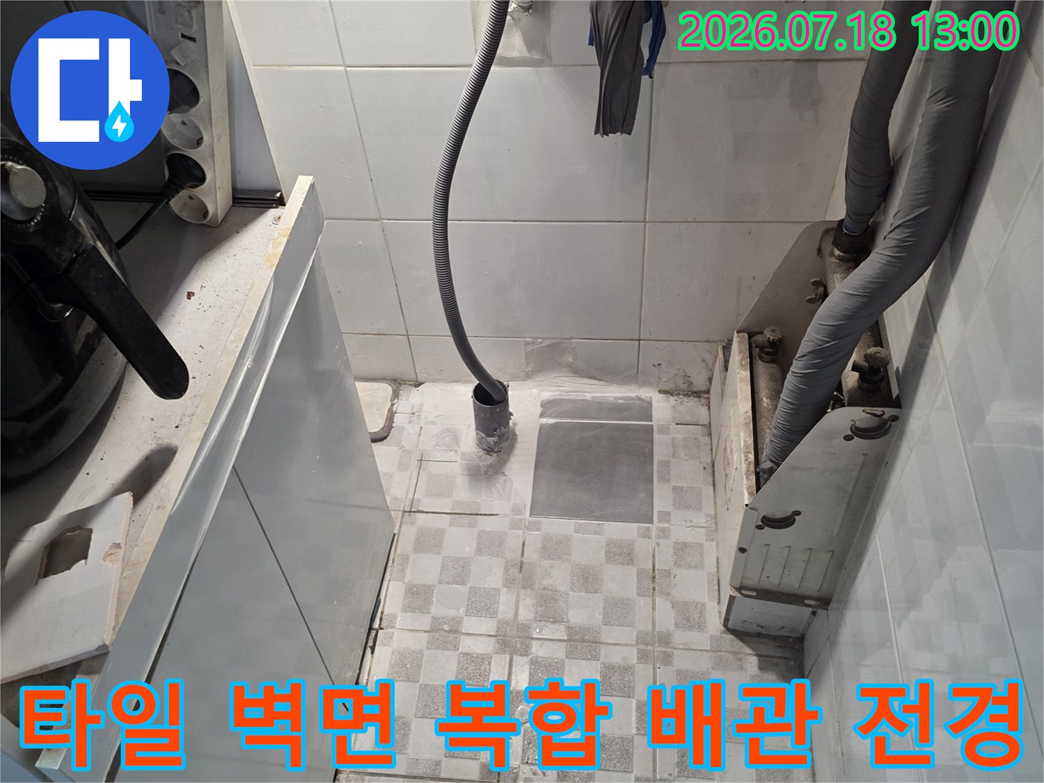 흰색 타일 배경에 회색 보온재 관과 노란색 호스가 설치된 모습