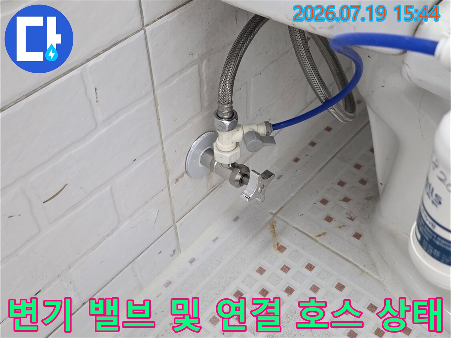 벽면에 고정된 급수 밸브와 변기로 들어가는 파란색 호스의 연결 지점