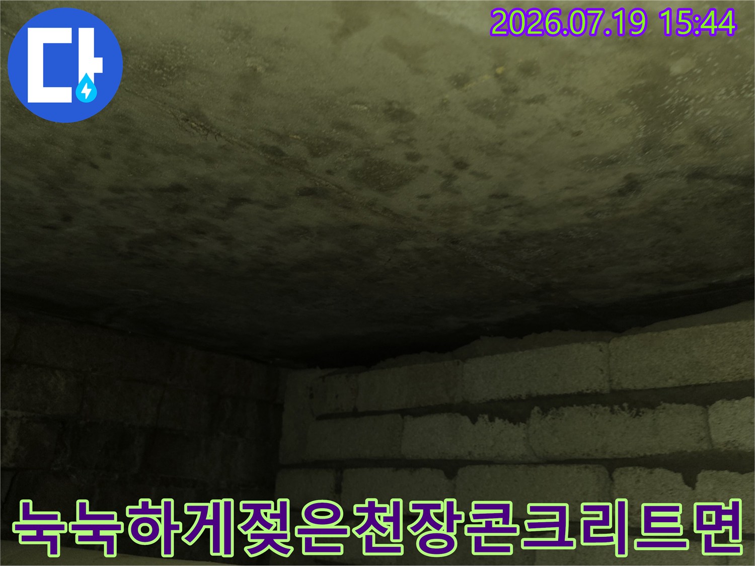 습기로 인해 색이 어둡게 변하고 얼룩덜룩해진 화장실 천장의 슬래브 모습