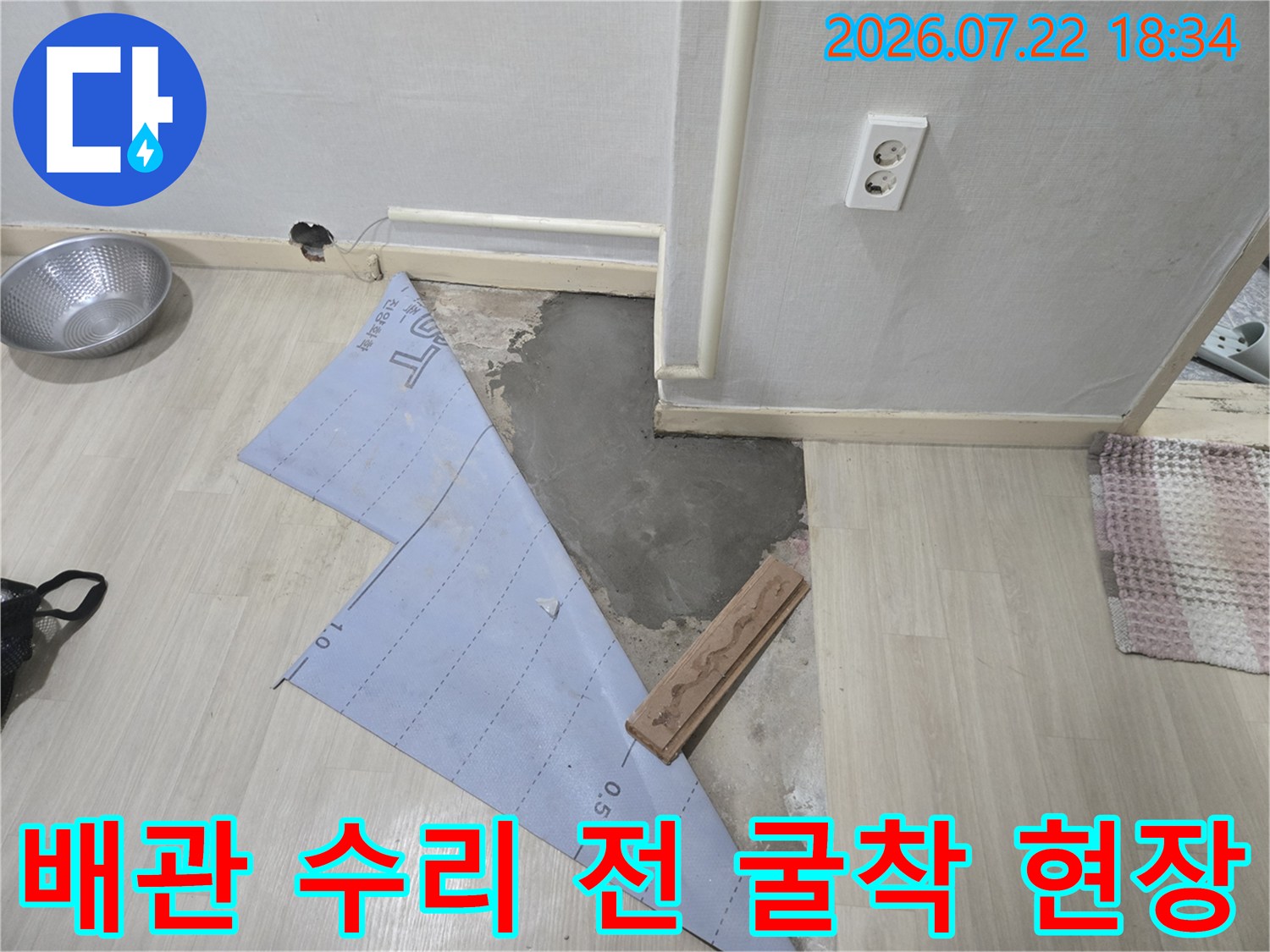 노출된 배관과 파낸 바닥면 그리고 작업 도면이 놓인 누수 공사 현장 사진