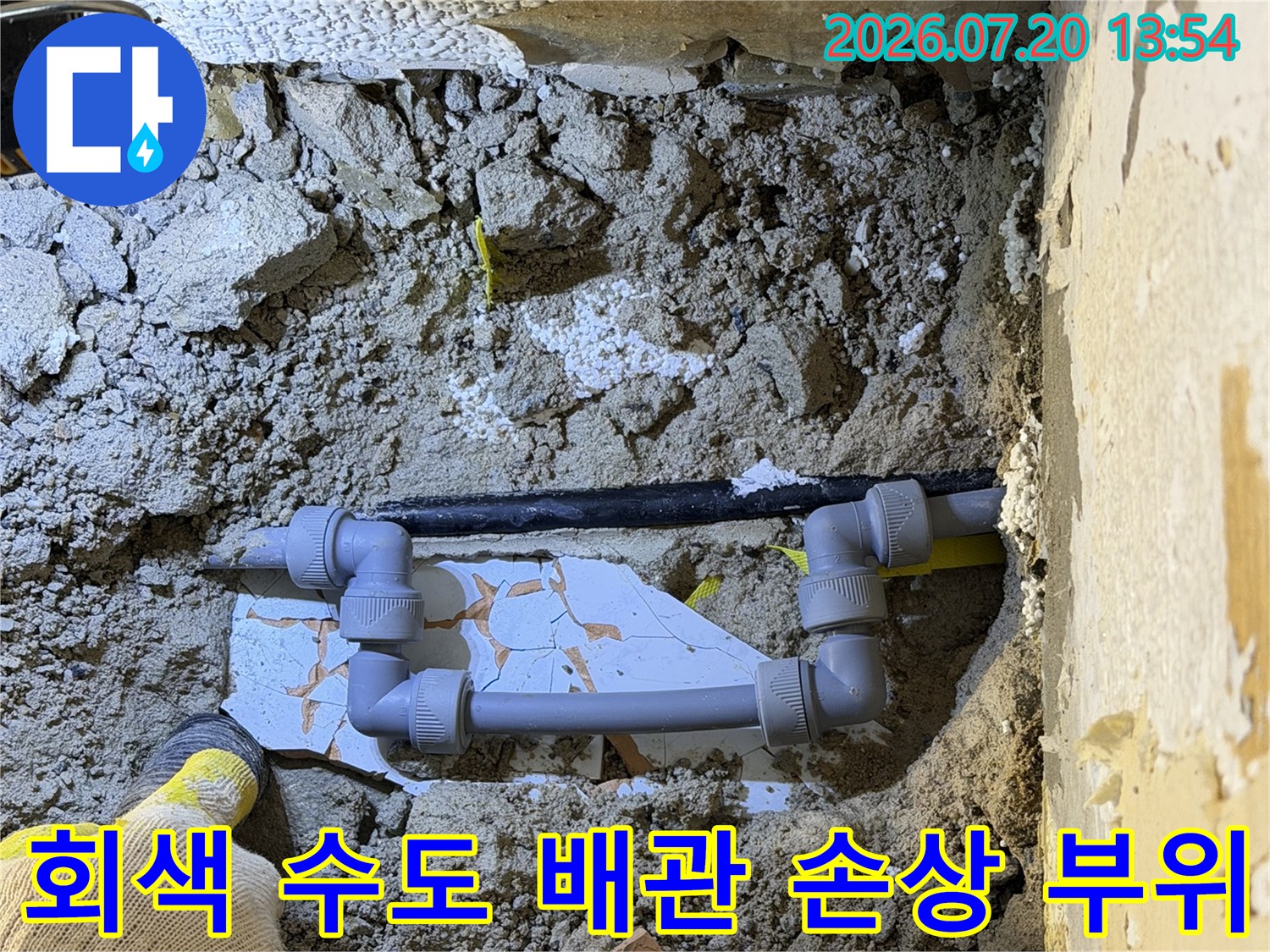 흙과 콘크리트 잔해 속에 매립되어 있던 회색 플라스틱 배관-파손 지점 노출
