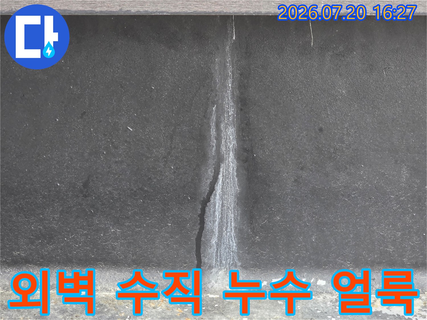회색 콘크리트 외벽에 수직으로 길게 형성된 누수 얼룩과 습기 흔적