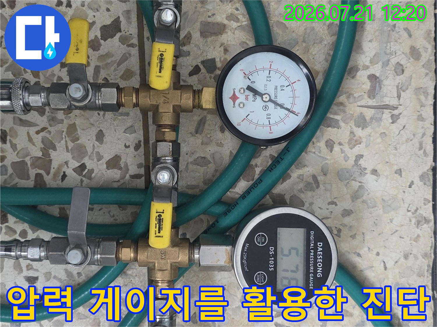 두 개의 압력계가 설치된 배관 분기점에 호스를 연결하여 수압을 점검하는 모습