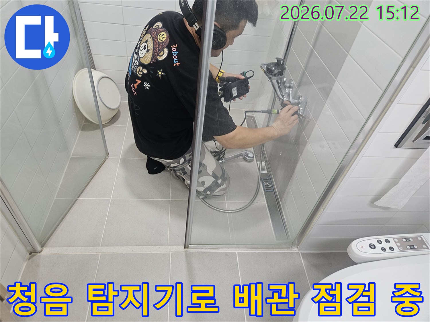 누수 전문가가-화장실 샤워기 밸브 쪽으로-탐지 장비를 밀착시켜 소리를 듣는 장면