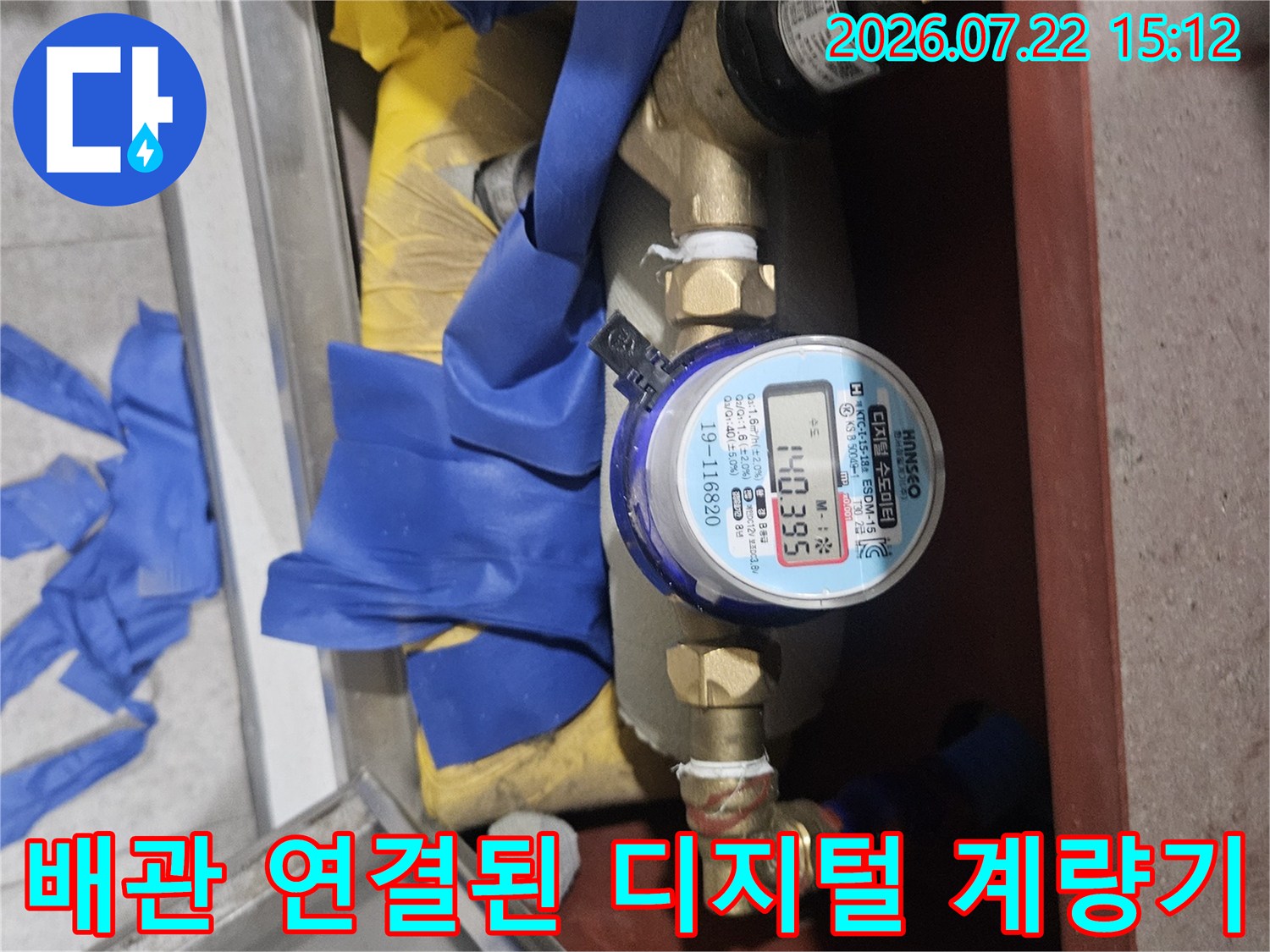 디지털 숫자가 선명하게 보이는 수도 계량기와 파란색 보온재가 감싸진 배관의 모습
