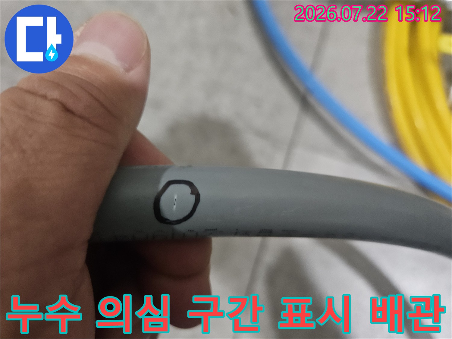 손으로 잡고 있는 회색 배관의 특정 부위에 검은색 동그라미가 그려진 모습