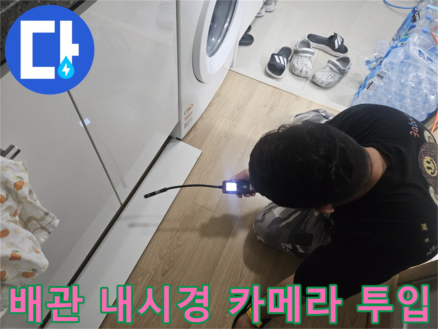 싱크대 하단 좁은 공간에 내시경 장비를 밀어 넣어 배관을 검사하는 모습입니다.