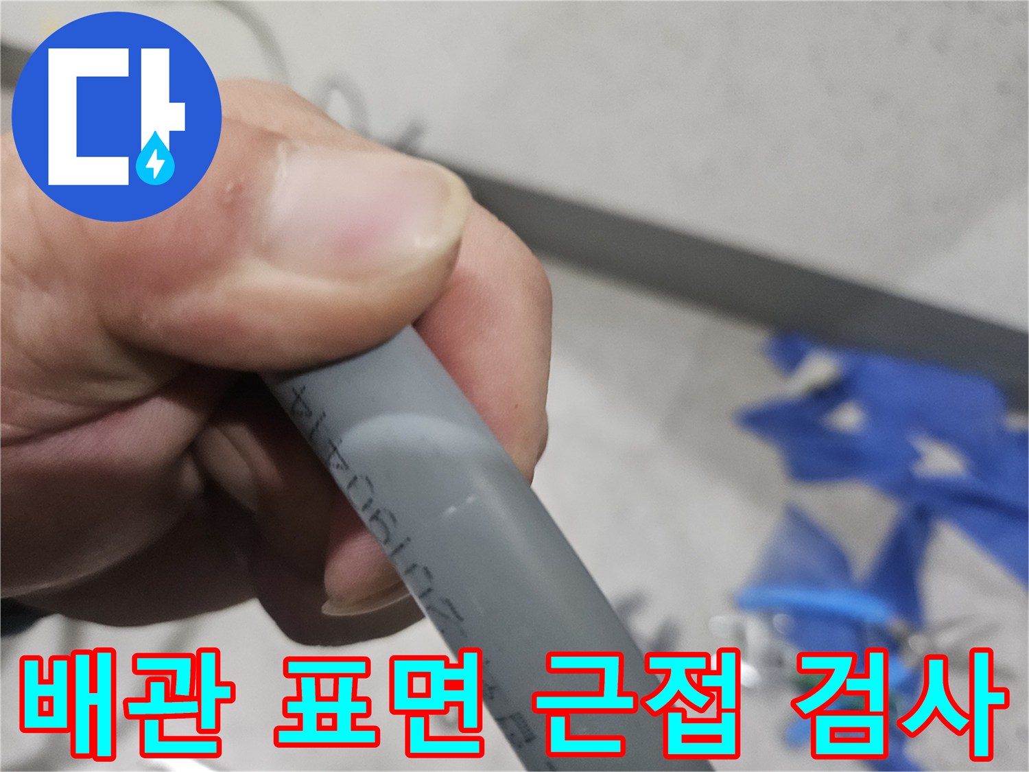 회색 배관의 표면을 손으로 잡고 면밀히 조사하는 모습-