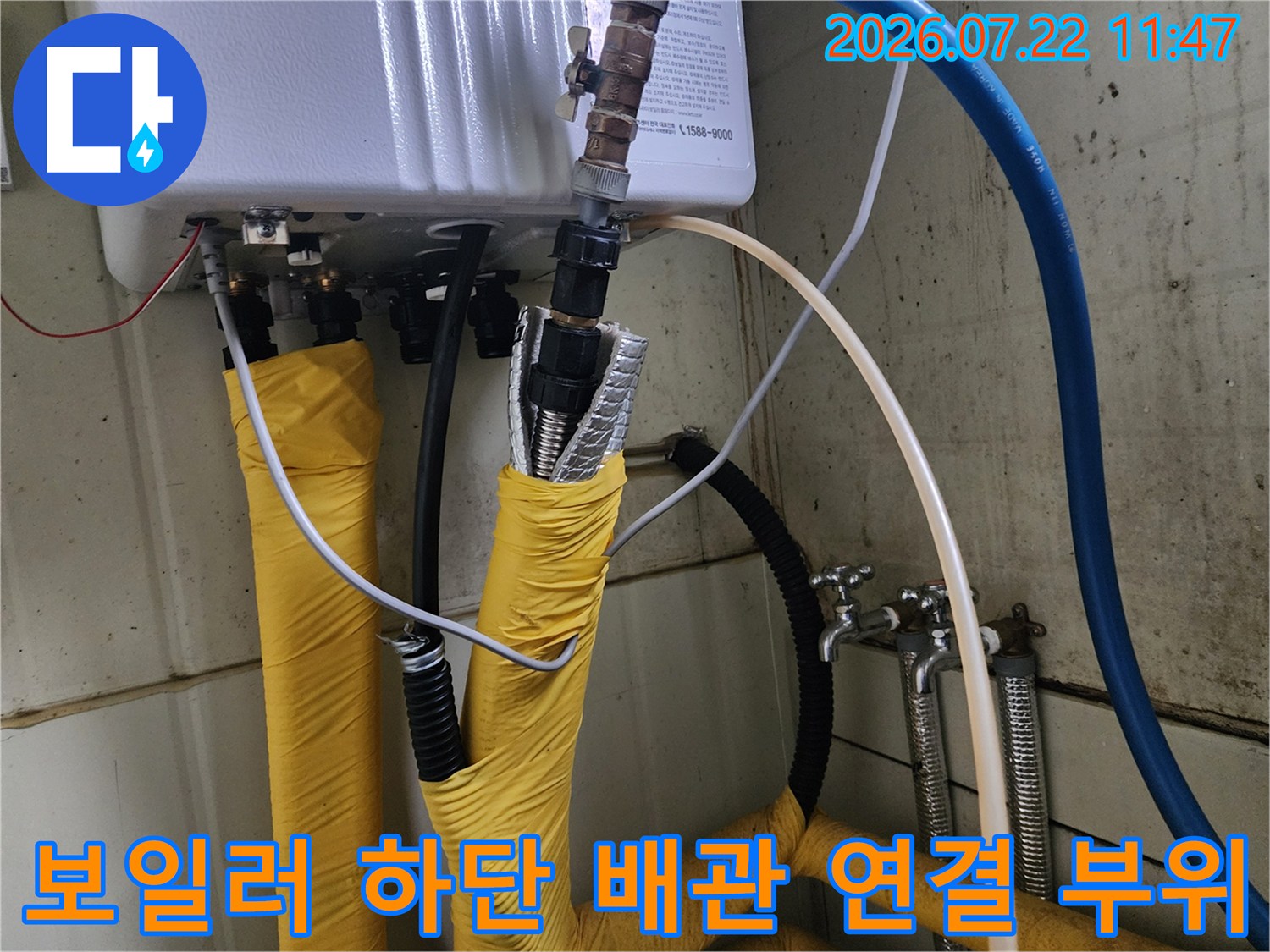 보일러 본체 하단에 연결된 은색 주름관과 노란색 보온재-마감 처리 상태