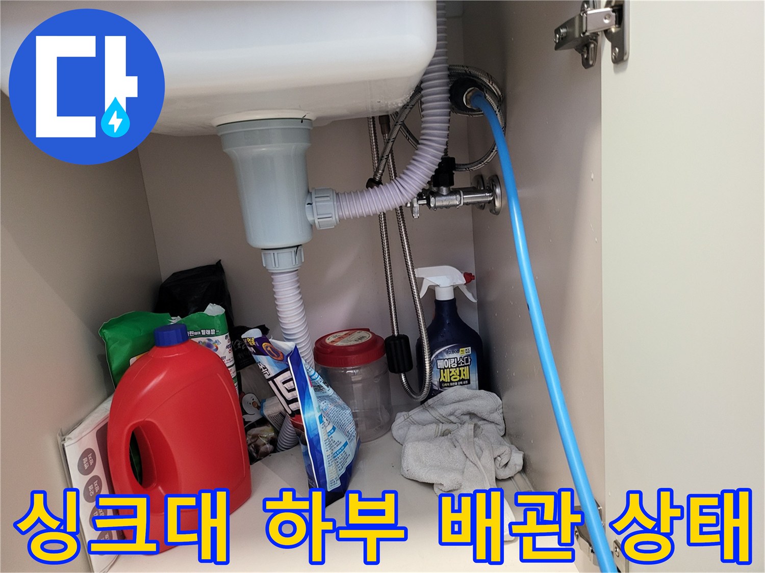 주방 싱크대 하부의 배수 호스와 급수 밸브 연결 부위 모습