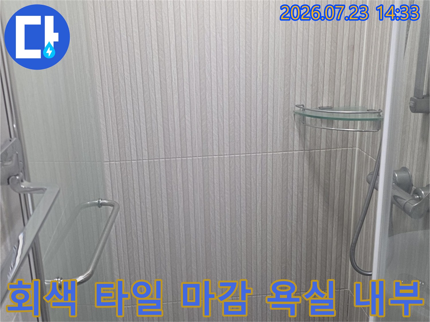 가로 패턴의 회색 타일이 시공된 샤워 공간-금속 소재의 안전 바와 투명 유리 파티션 설치 모습